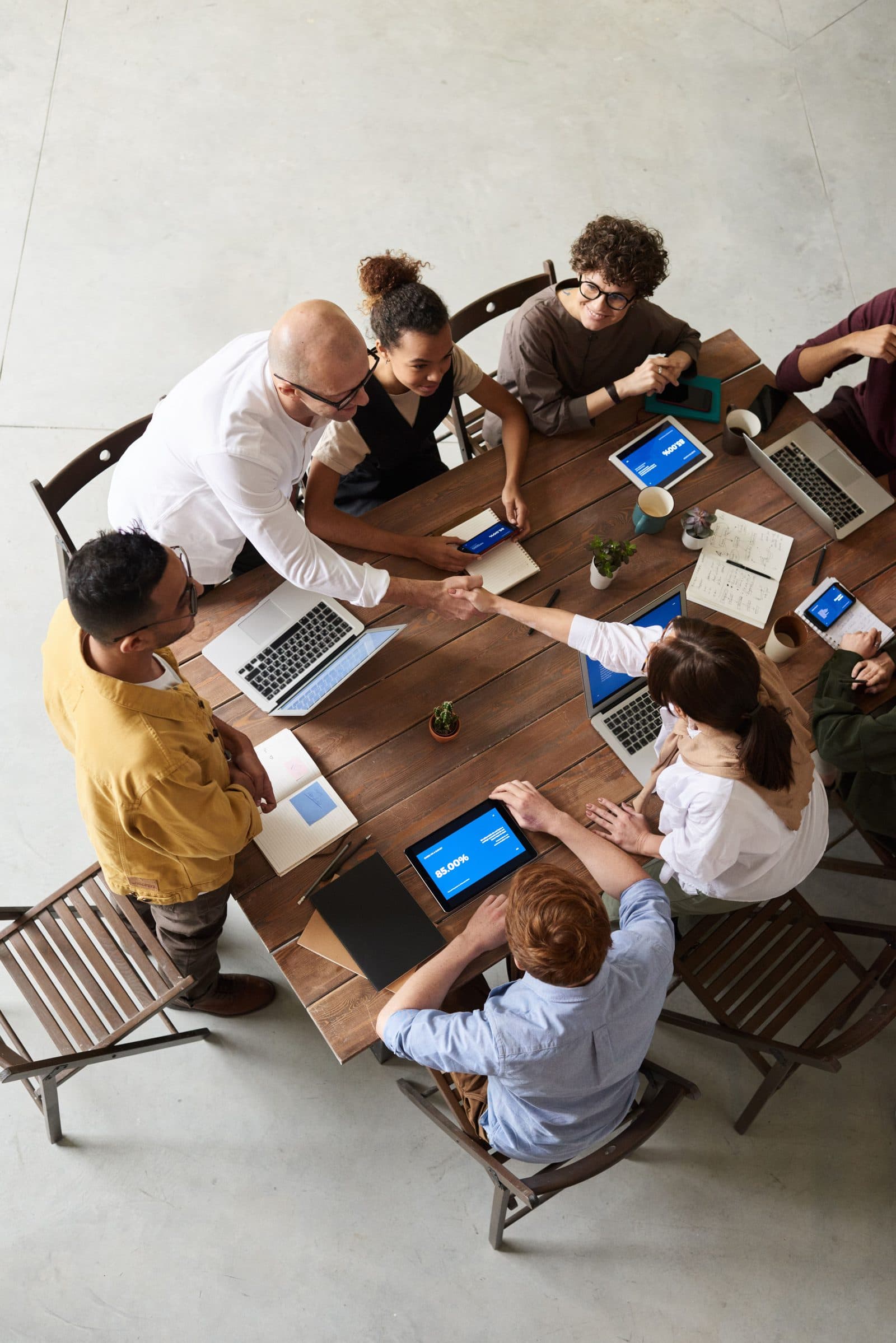 A business team around a table shaking hands over a deal